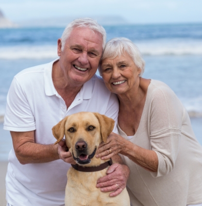 An elderly couple at the beach with their dog